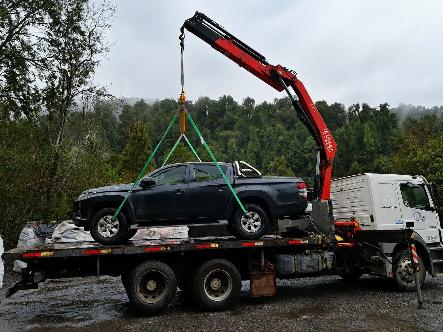 Grúa izando una camioneta sobre la plataforma del camión en la Carretera Austral